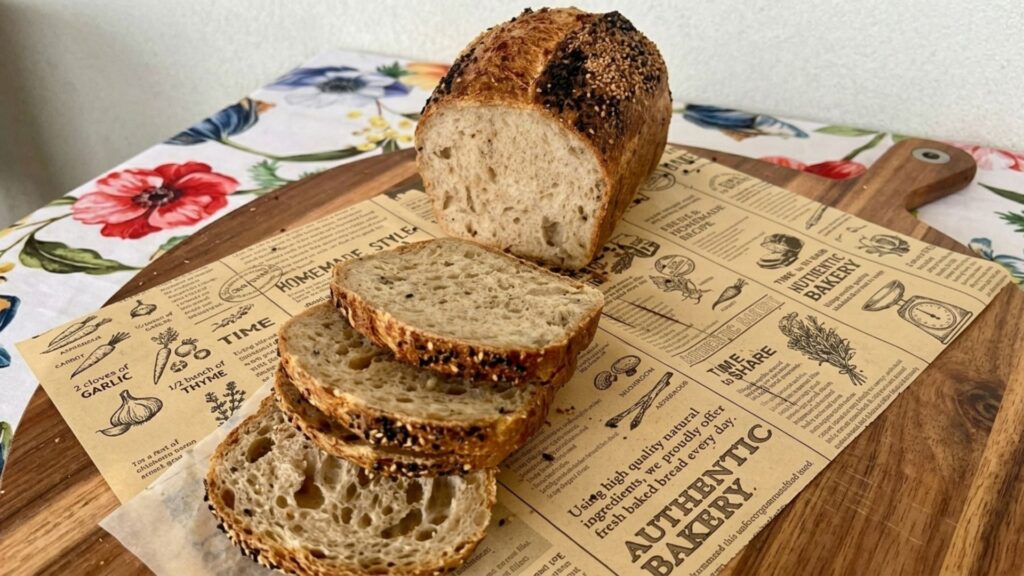 Seeded whole wheat sourdough sandwich bread, sliced, on a wooden board