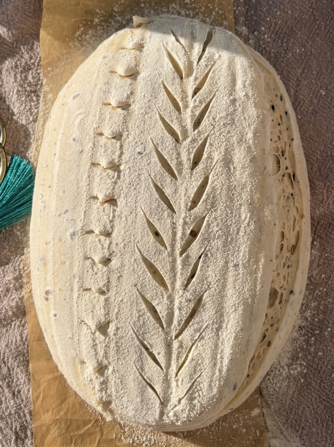 Unbaked sourdough loaf with a wheat-stalk pattern scored into the surface before baking