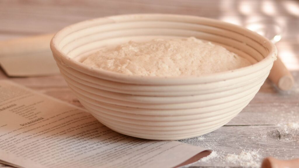 Flat lay of sourdough baking tools including a scale, banneton, and Dutch oven